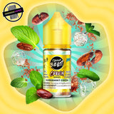A 30ml bottle of Flavour Beast Cravin' Series E-Liquid in peppermint cocoa flavour. The bottle is surrounded by mint leaves, cocoa beans, and ice cubes. Underground Vapes Woodstock and London