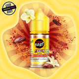 A 30ml bottle of Flavour Beast Cravin' Series E-Liquid in red bake flavour. The bottle is surrounded by cocoa beans and vanilla flowers. Underground Vapes Woodstock and London